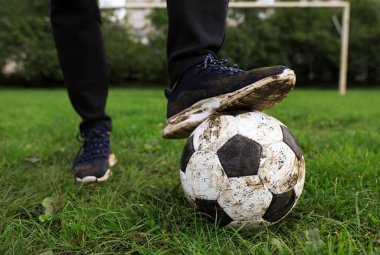 Yeşil çimlerin üzerinde kirli futbol topu olan adam, yakın plan.