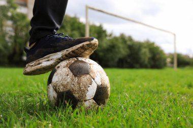 Yeşil çimlerin üzerinde kirli futbol topu olan bir adam, yakın plan. Metin için boşluk
