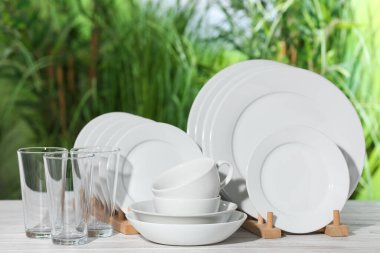Set of clean dishware on white table against blurred background clipart