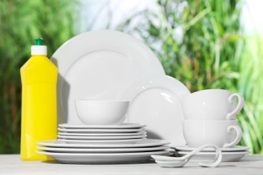 Temiz bulaşık ve deterjan seti beyaz masada bulanık arka planda