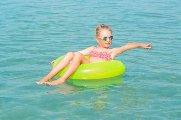 Happy little girl with inflatable ring in sea on sunny day