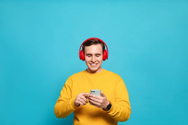 Beau Jeune Homme Avec Écouteurs Smartphone Moderne Sur Fond Bleu — Photo
