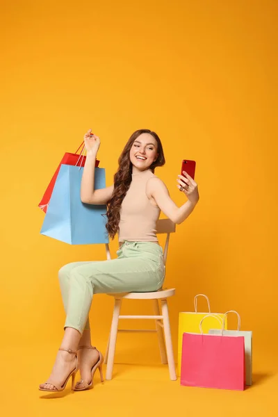 Hermosa Mujer Tomando Selfie Mientras Sostiene Coloridos Bolsos Compras Silla —  Fotos de Stock