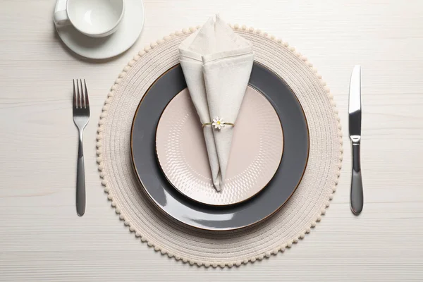 stock image Plates with fabric napkin, decorative ring and cutlery on white wooden table, flat lay