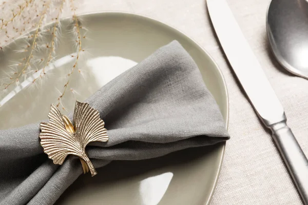 Gray fabric napkin and decorative ring for table setting on plate, closeup