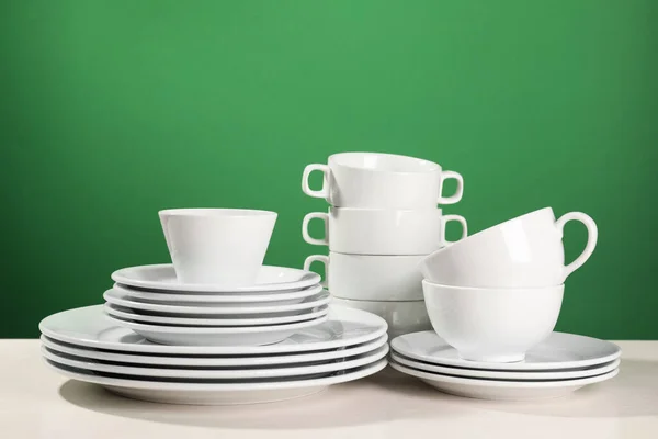 Yeşil Arkaplana Karşı Beyaz Masada Temiz Bulaşık Takımı — Stok fotoğraf