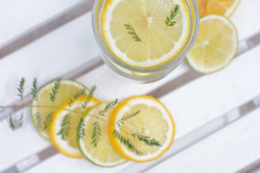 Lezzetli ferahlatıcı limonata ve beyaz ahşap masa üzerinde narenciye parçaları.