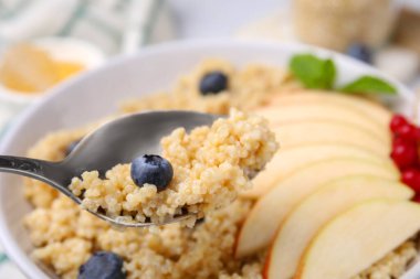 Bir kaşık lezzetli kinoa ve yaban mersini kasenin üstünde, yakın plan. Metin için boşluk