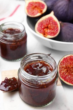 Cam kavanozlar dolusu lezzetli incir reçeli ve beyaz fayanslı meyveler.