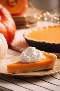 Piece of fresh homemade pumpkin pie with whipped cream on table