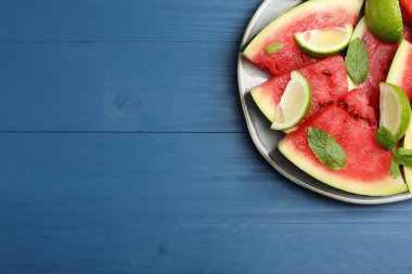 Mavi ahşap masada sulu karpuz ve limonlu tabak, üst manzara. Metin için boşluk