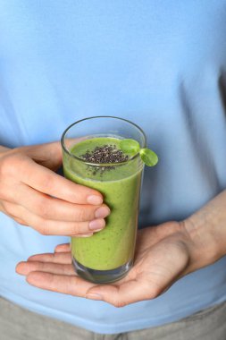 Elinde taze yeşil smoothie bardağıyla Chia tohumlu bir kadın, yakın plan.