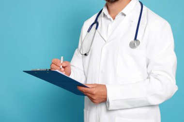 Doctor with stethoscope and clipboard on light blue background, closeup
