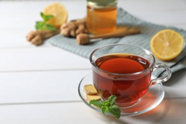 Bir fincan lezzetli zencefilli çay ve malzemeler beyaz ahşap masada, metin için yer var.