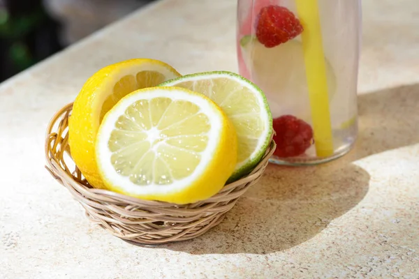 Citrus fruits and refreshing tasty lemonade served in glass bottle on beige table
