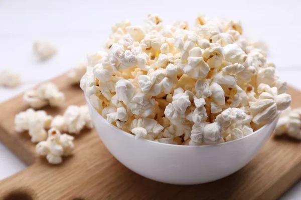 stock image Tasty popcorn in bowl on wooden board, closeup