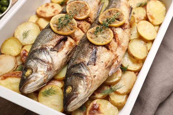 stock image Baking tray with delicious baked sea bass fish and potatoes, closeup