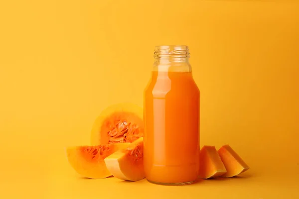ガラス瓶でおいしいカボチャジュースとオレンジの背景にカボチャをカット — ストック写真