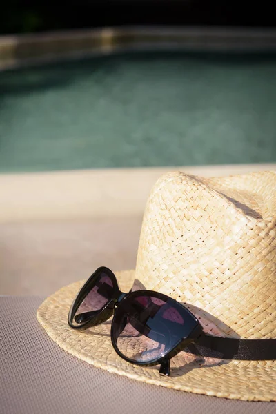 stock image Stylish hat and sunglasses near outdoor swimming pool