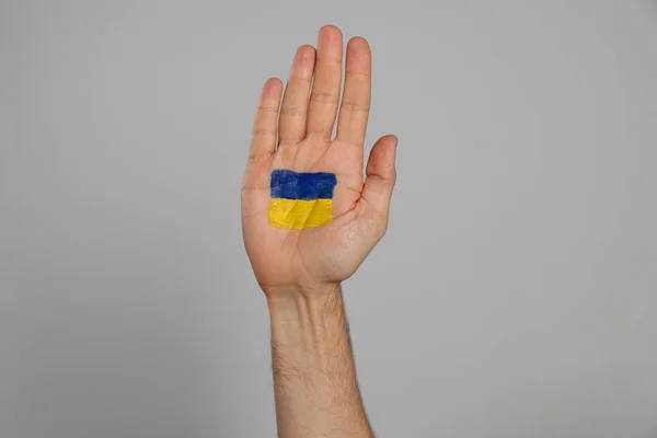 ライトグレーの背景に手のひらにウクライナの旗を描く男 クローズアップ — ストック写真