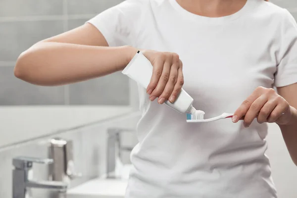 バスルームのブラシに歯磨き粉を適用する女性 クローズアップ — ストック写真