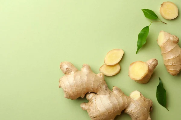 Fresh ginger with leaves on light pale green background, flat lay. Space for text