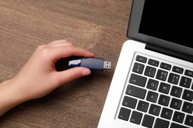 Tahta masada USB belleği bilgisayara bağlayan kadın, yakın plan.