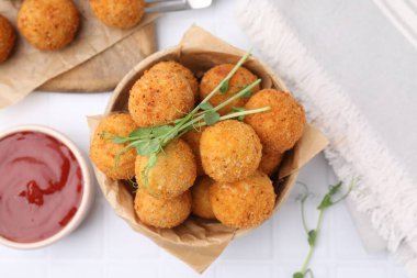 Bir kase lezzetli kızarmış tofu topları bezelye filizi ve beyaz fayanslı masada sos.