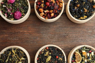 Tahta masadaki kaselerde farklı türde kuru bitkisel çay, düz yatak. Metin için boşluk