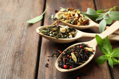 Tahta masada kurutulmuş çay yapraklı kaşıklar, yakın plan. Metin için boşluk