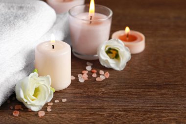 Ahşap masa üzerinde yanan mumlar ve çiçekler olan güzel bir spa kompozisyonu. Metin için boşluk
