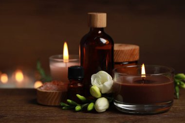 Güzel bir spa kompozisyonu yanan mumlar, farklı bakım ürünleri ve ahşap masa üzerinde çiçekler.