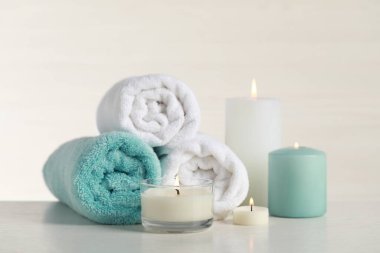 Güzel bir spa kompozisyonu, yanan mumlar ve beyaz masaya sarılmış havlular.
