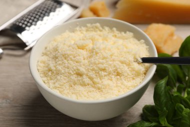 Beyaz ahşap masada kasede nefis rendelenmiş parmesan peyniri, yakın plan.