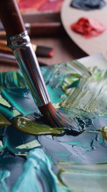 Sanatçının tuvalini karışık boyalarla fırçalayın, yakın plan.