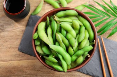 Tahta masada soya sosuyla servis edilen kabuklu yeşil edamame fasulyeleri.
