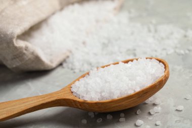 Açık gri mermer masadaki ahşap kaşıkta doğal deniz tuzu. Yakın plan.