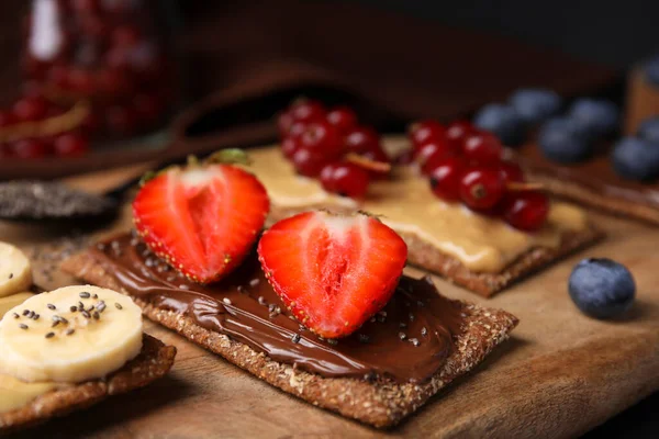 stock image Fresh crunchy rye crispbreads with different toppings on wooden board, closeup