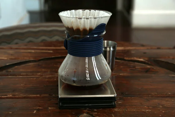 Cup with wave dripper and coffee on wooden table in cafe