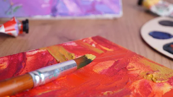 탁자에 페인트와 붓으로 뒤섞인 예술가의 캔버스 클로즈업 — 스톡 사진