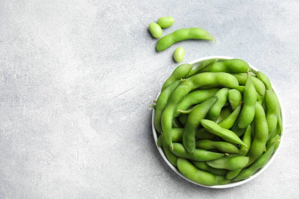 Green edamame beans in pods on light grey table, flat lay. Space for text