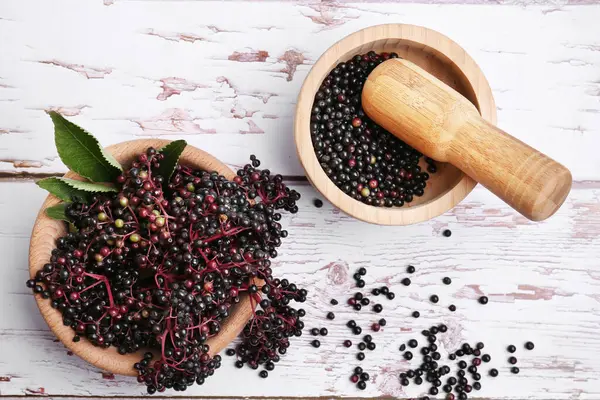 stock image Tasty elderberries (Sambucus) on white wooden table, flat lay