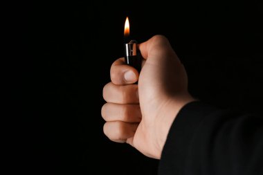 Siyah arka planda çakmak tutan adam, yakın plan