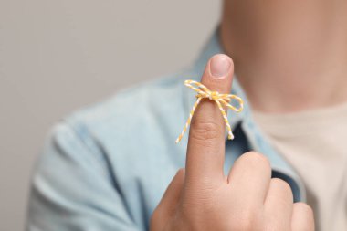 Açık gri arkaplanı hatırlatmak için bağlı yay ile işaret parmağı gösteren adam, ele odaklan