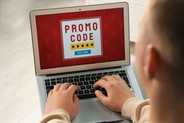 Bilgisayarlı bir adam içeriden alışveriş yaparken tanıtım kodunu etkinleştiriyor.