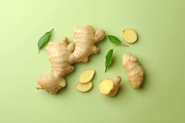 Fresh ginger with leaves on light pale green background, flat lay
