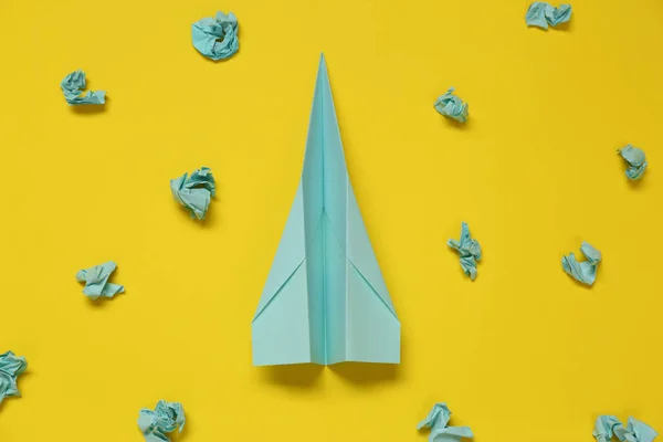 Flat lay composition with handmade plane and many crumpled pieces of paper on yellow background