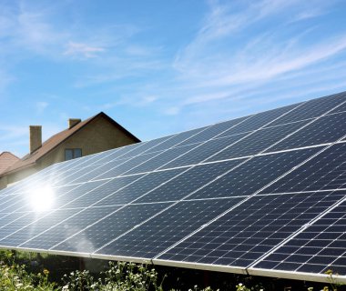 Güneşli bir günde mavi gökyüzünün altındaki evlerin yakınındaki güneş panelleri. Alternatif enerji kaynağı