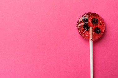 Sweet colorful lollipop with berries on pink background, top view. Space for text