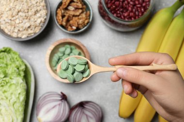 Masada elinde bir kaşık dolusu hapla yemek yiyen bir kadın. Prebiyotik takviyeler